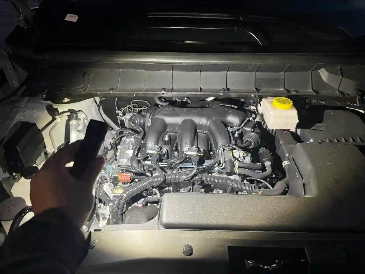 Rechargeable magnetic work light illuminating an engine bay during automotive repair